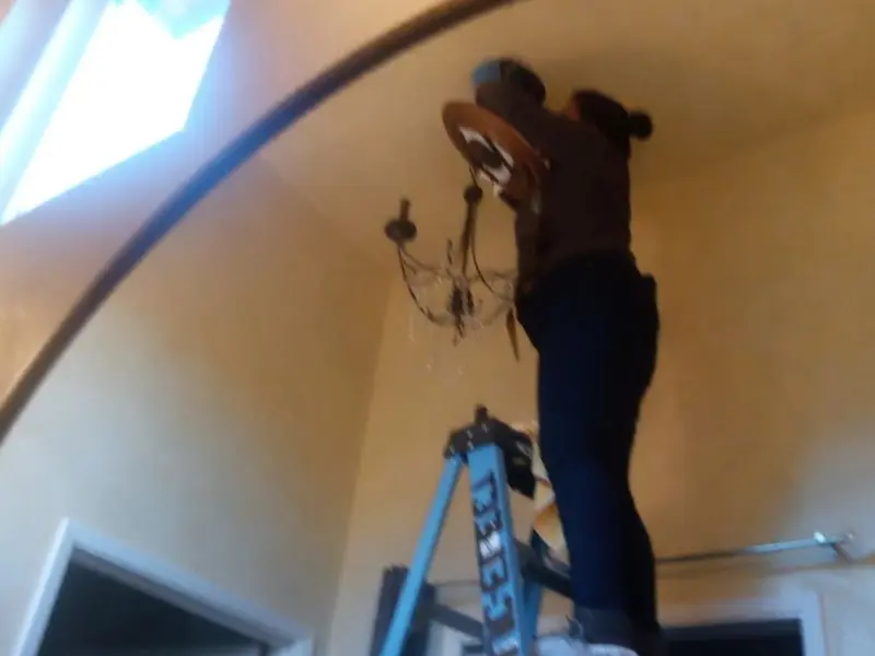 Electrician installing a chandelier in a Bay City residence